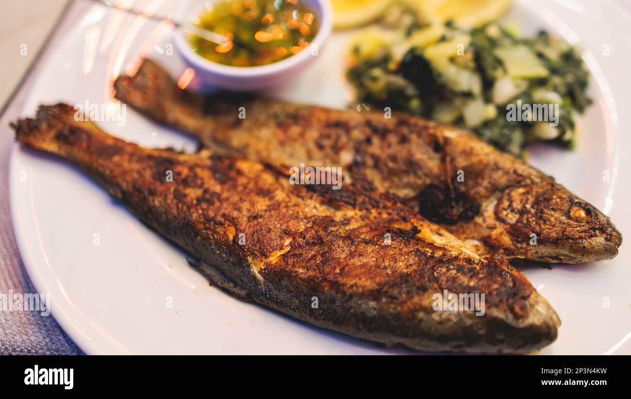 Fried grilled trout, roasted pastrmka fish on plate with spinach and