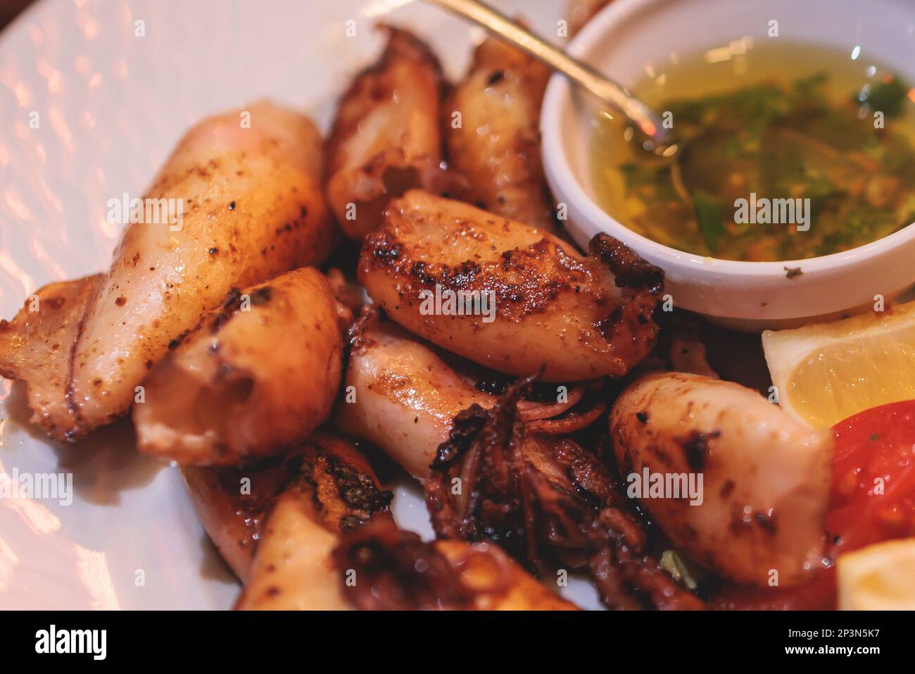 Fried grilled baby squids on a plate with garlic, lemon and mashed