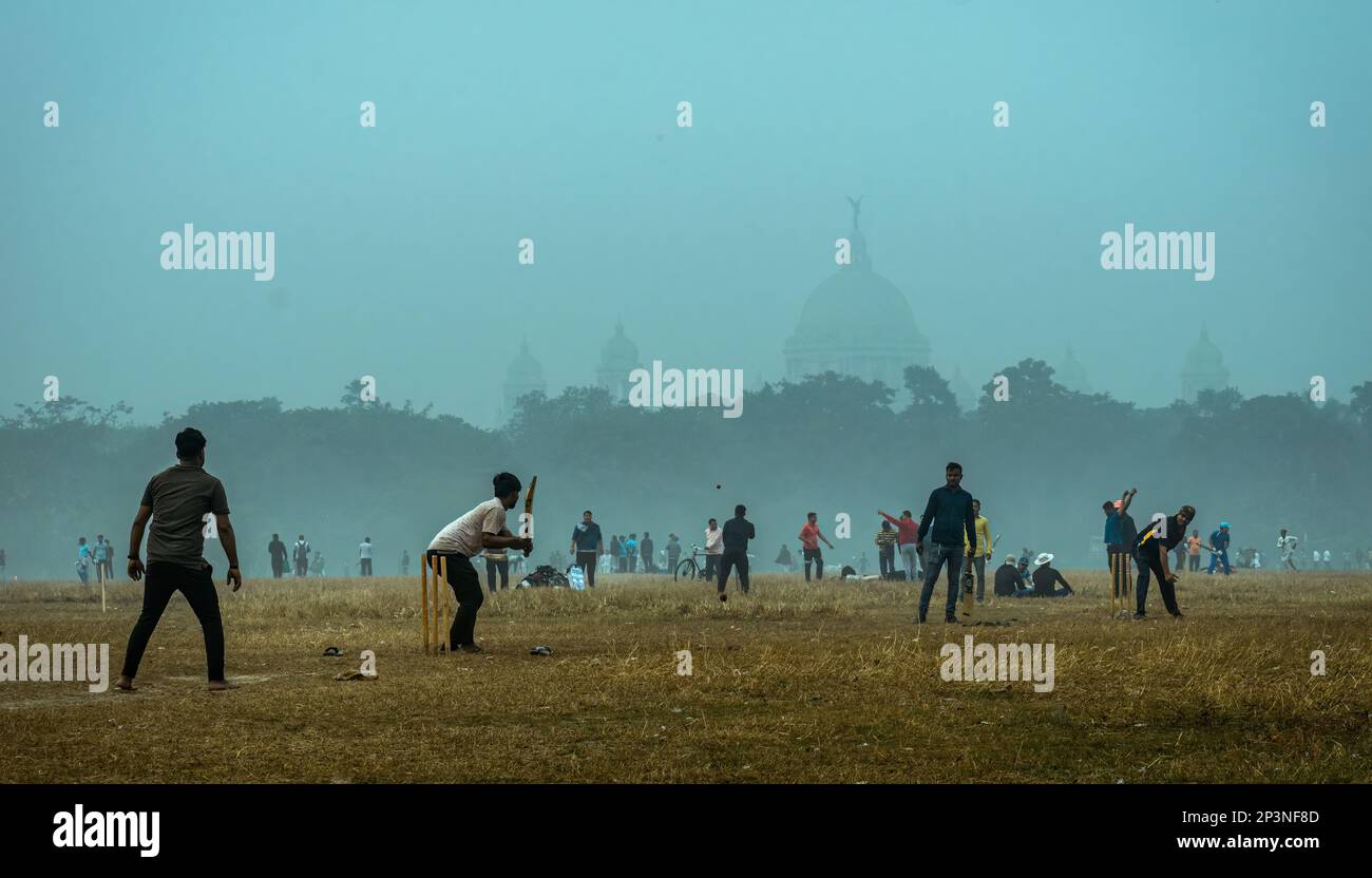 Kolkata, India - January 15, 2023: Local boys playing an unorganized cricket match in a misty winter morning. Shallow depth of field. Stock Photo