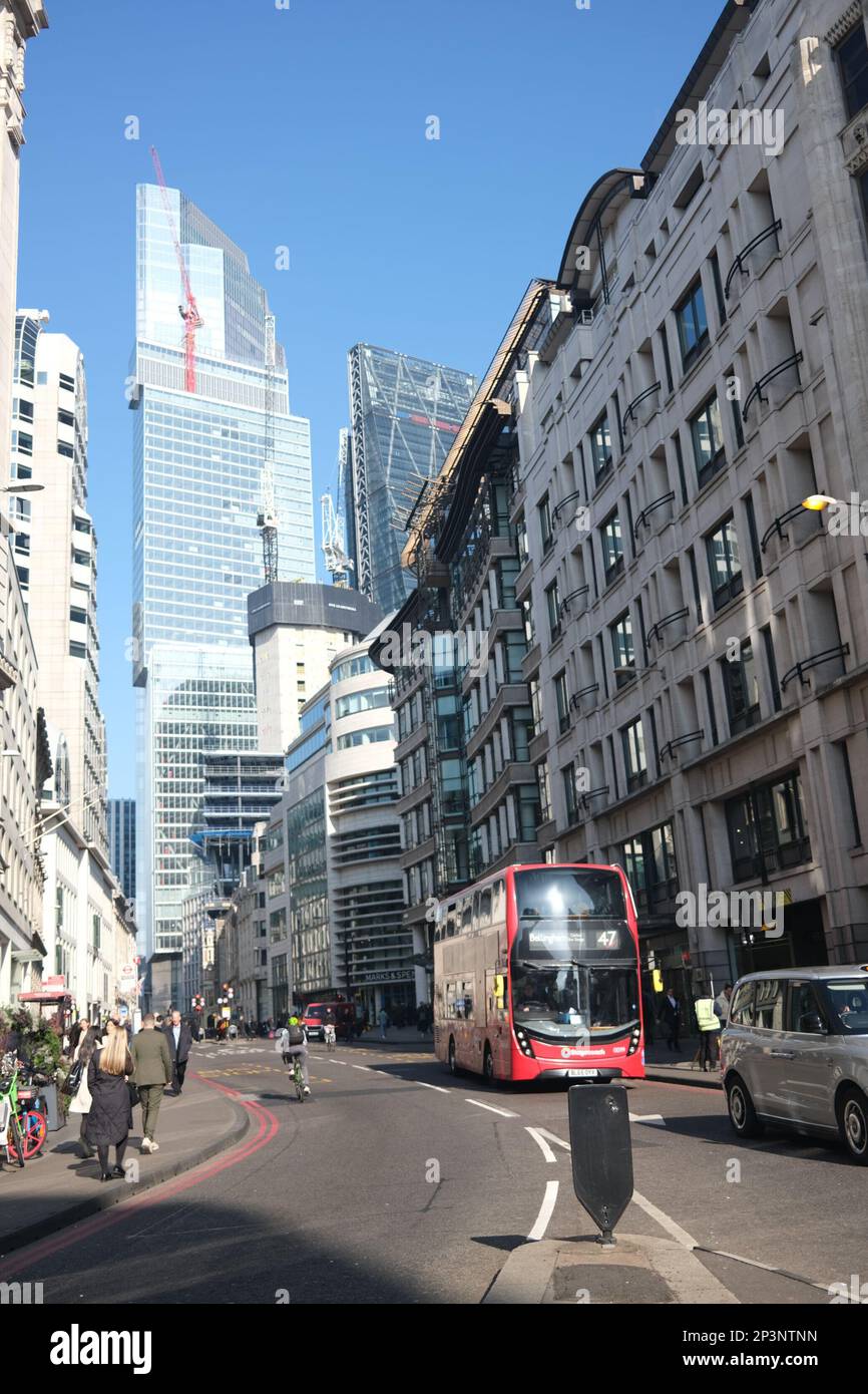 A street scene in central London on a sunny early spring day in March 2023. A red bus approaches surrounded by a blend of various architectural styles Stock Photo