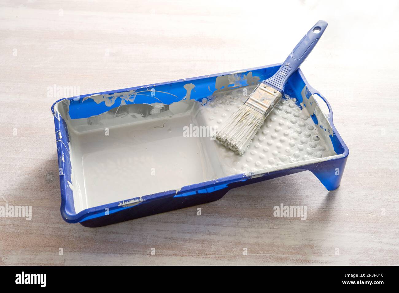 Blue paint tray with light gray lacquer and a brush on a wooden table, craft concept for renovation, painting and do it yourself, copy space, selected Stock Photo