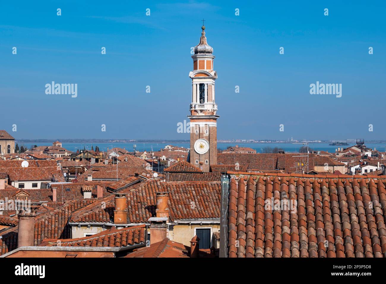 A clock tower rises above the rooftops of Venice, Italy Stock Photo
