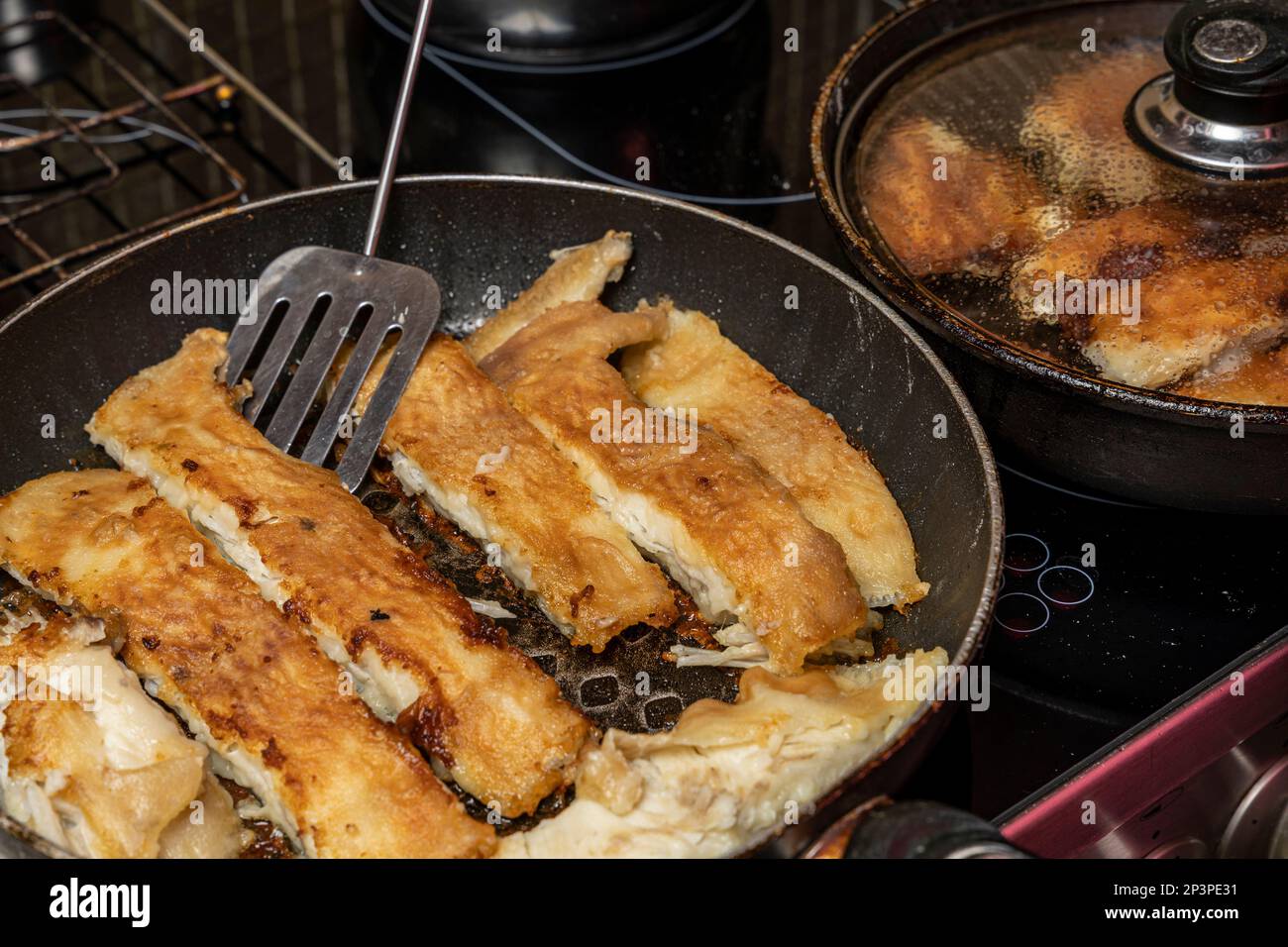 the cook checks the readiness of the fish with a fork Stock Photo - Alamy