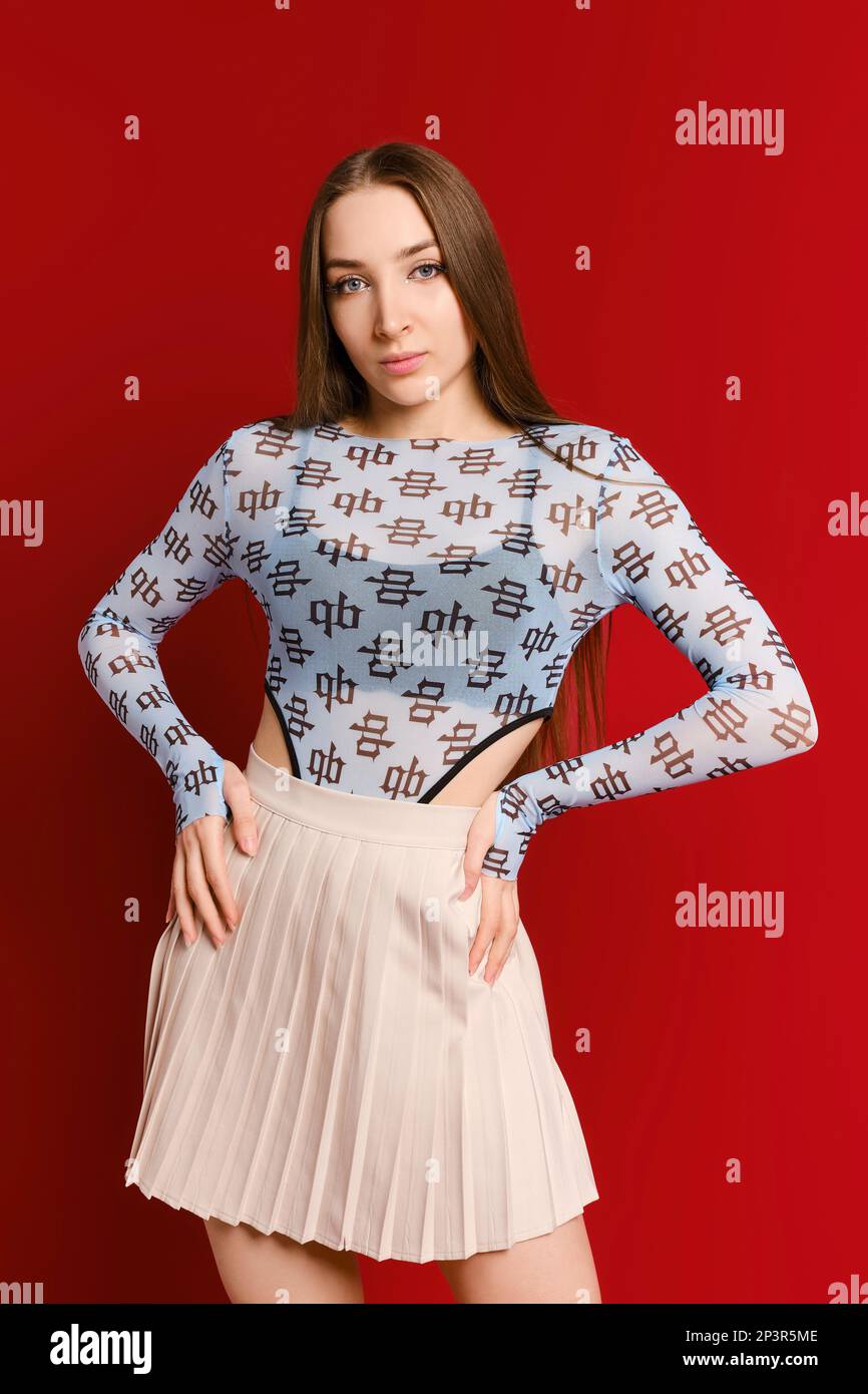 Young active woman in body suit and tennis skirt posing in red studio Stock Photo