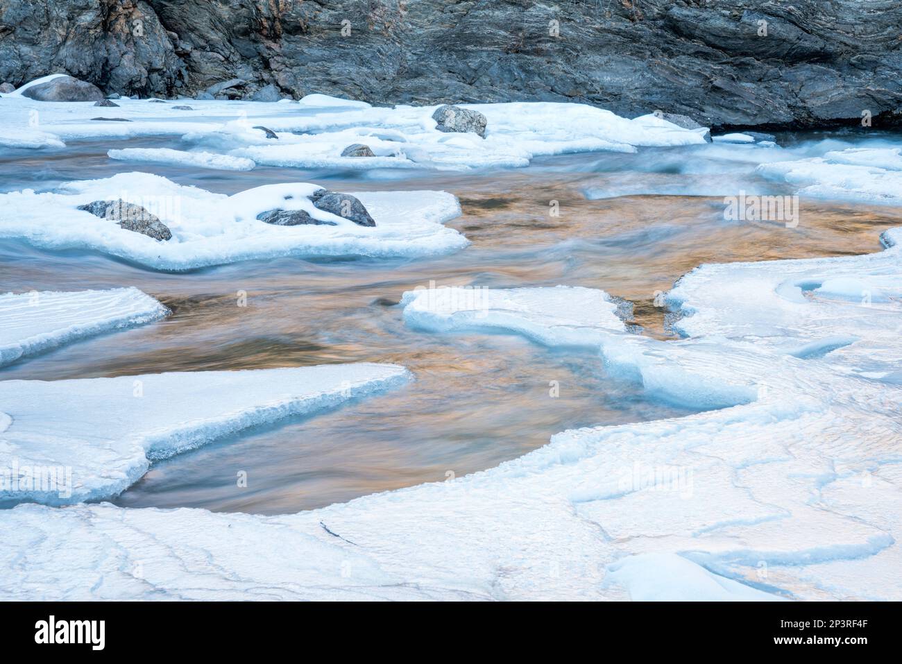 partially frozen Poudre River in northern Colorado - ice, water and rock abstract Stock Photo