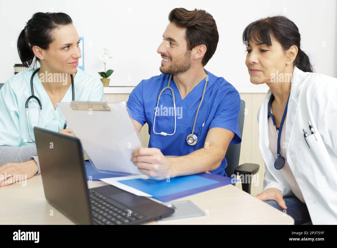 three medical staff sat around desk conferring Stock Photo Alamy