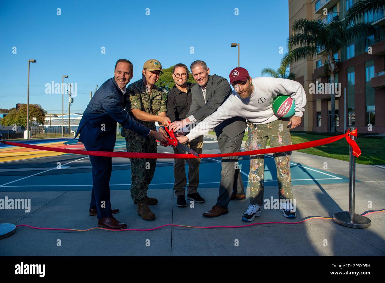 230126-N-XG173-1491 NAVAL BASE SAN DIEGO (Jan. 26, 2023) From left to right;  Michael Sheehan, Capt. Ted Carlson, Monty Montgomery, Adam Hay and Dan Peterson prepare to cut the ceremonial ribbon during Pacific Beacon’s unveiling of the Project Backboard basketball court. The ceremony celebrated a culmination of almost two years of collaboration between Pacific Beacon’s bachelor housing team, The Michaels Organization and Project Backboard to create a unique backdrop for Sailors to enjoy while playing basketball. Project Backboard is a 501(c)(3) non-profit organization that works with communiti Stock Photo