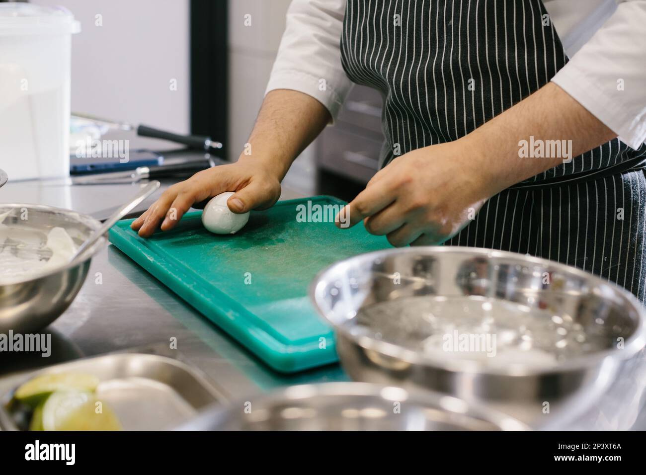 Close up. A male cook is cleaning boiled eggs in the kitchen of a restaurant. Stock Photo
