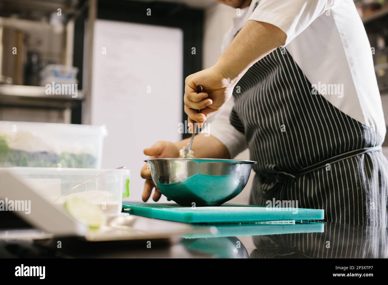 Close up. A male cook prepares pancake batter in a metal bowl in the kitchen of a restaurant. Stock Photo