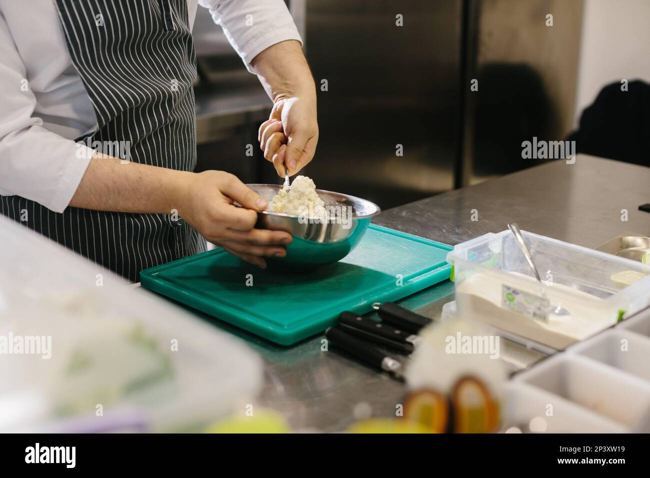 Close up. A male cook prepares pancake batter in a metal bowl in the kitchen of a restaurant. Stock Photo