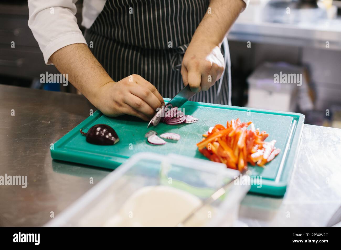 Close up, male chef cuts vegetables in restaurant. Stock Photo