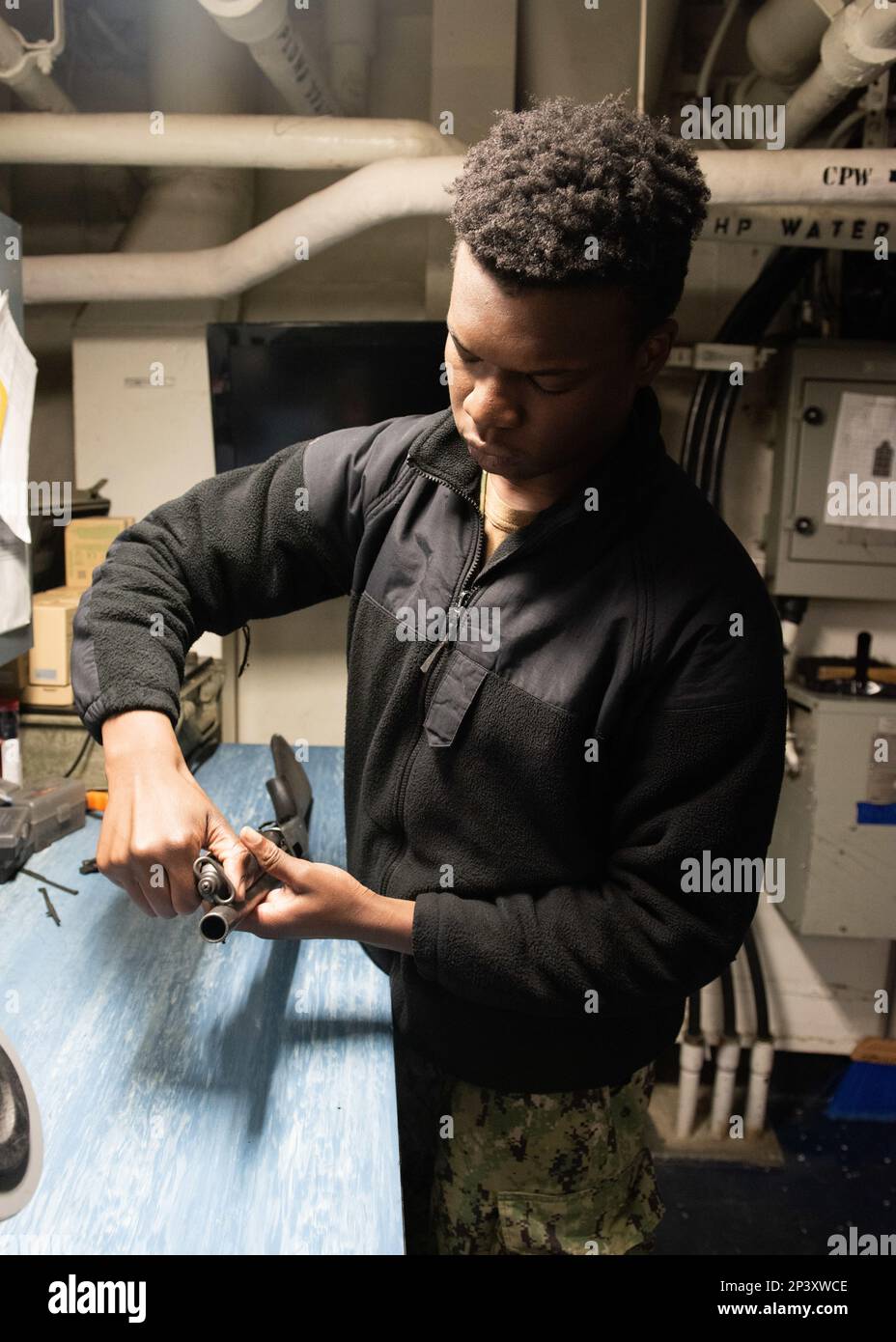 NAVAL BASE KITSAP-BREMERTON, Wash. (Jan. 19, 2023) – U.S. Navy Airman Duada Olaoluwa, from Detroit, disassembles an M500 shotgun aboard the Nimitz-class aircraft carrier USS Theodore Roosevelt (CVN 71) Jan. 19, 2023. Theodore Roosevelt is in a docking planned incremental availability at Puget Sound Naval Shipyard and Intermediate Maintenance Facility where the ship is receiving scheduled maintenance and upgrades. Stock Photo