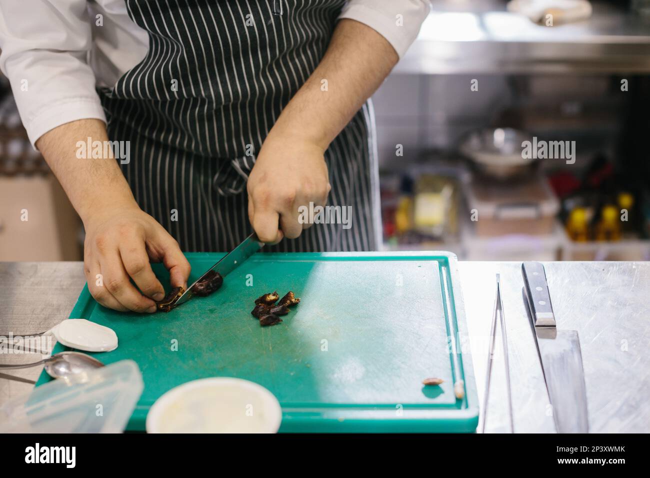 The process of making muesli in a restaurant, the male chef cuts dates in the kitchen. Stock Photo