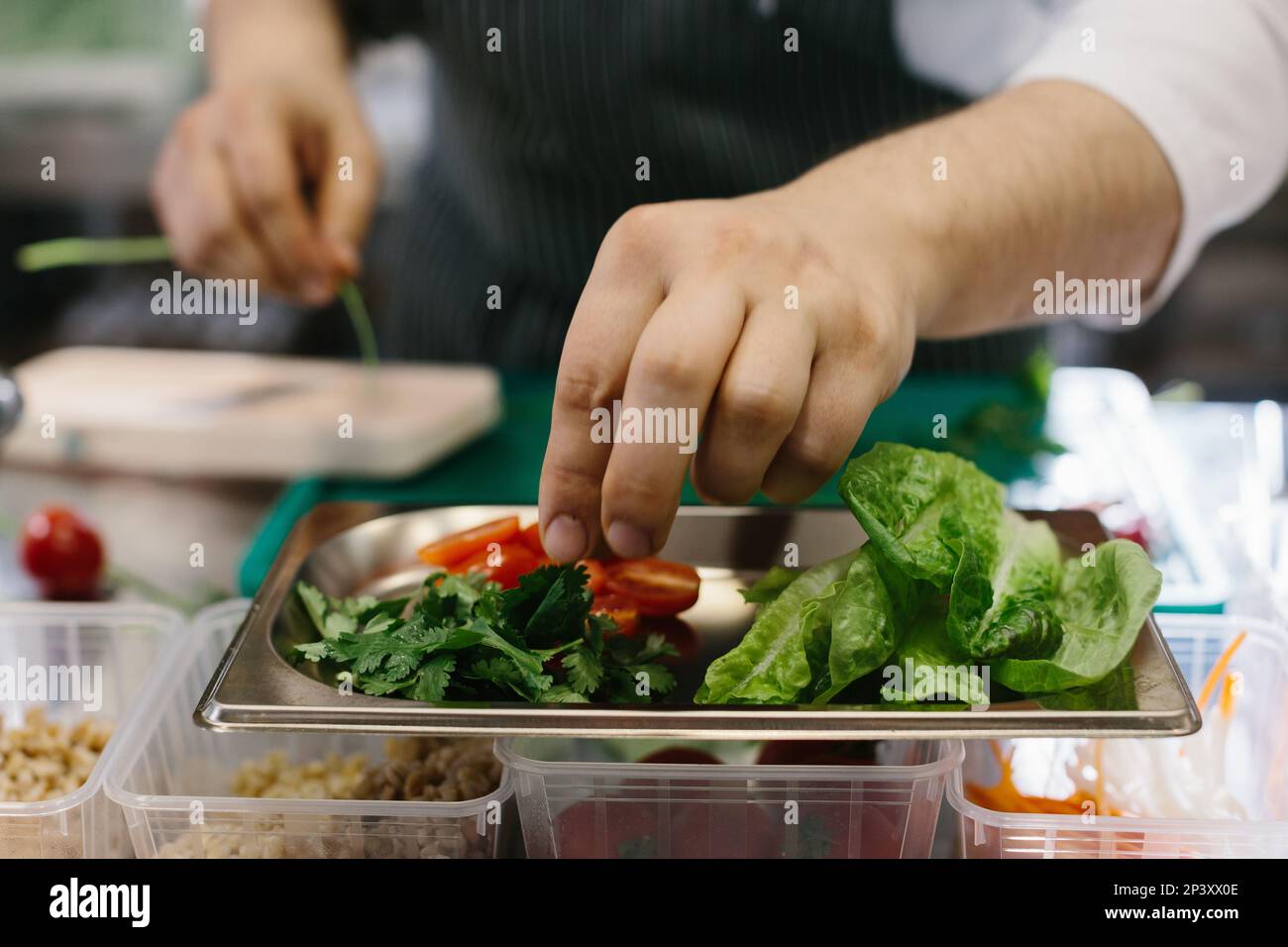 Preparing vegetables for a delicious bowl dish: a male chef in a contemporary restaurant kitchen. Stock Photo