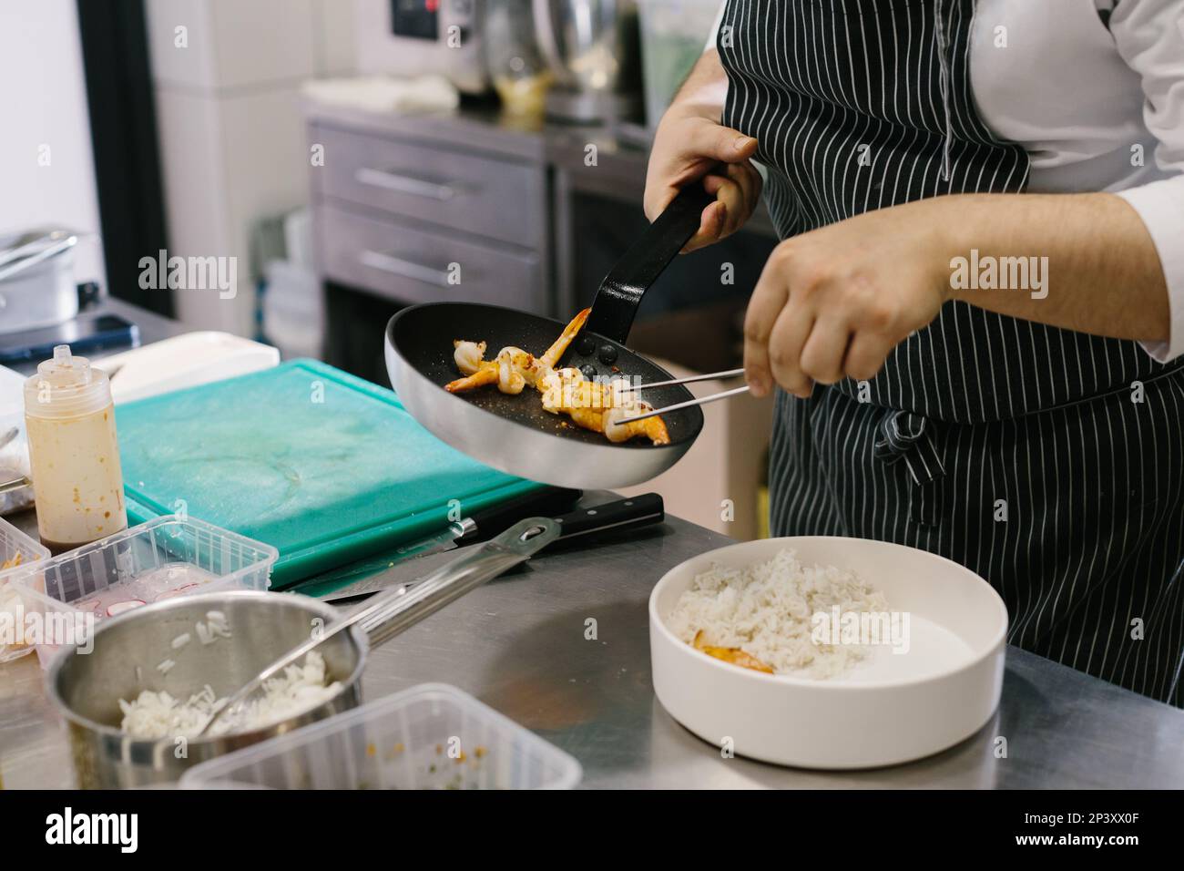 Preparing a bowl of seafood, a male chef prepares a delicious dish in a restaurant kitchen. Stock Photo