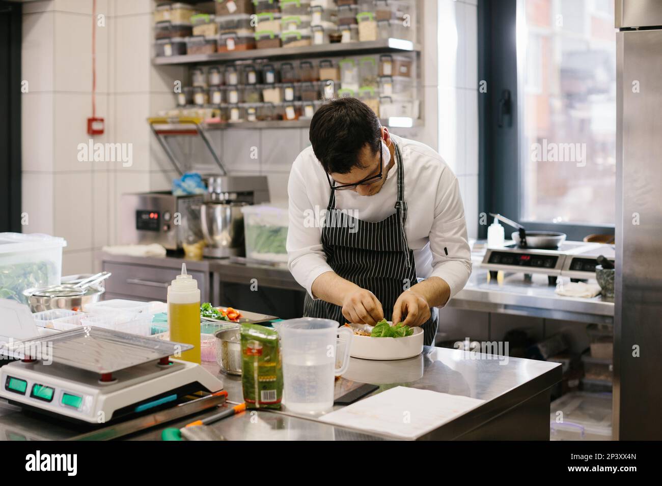 The chef prepares food in the modern spacious kitchen. Stock Photo