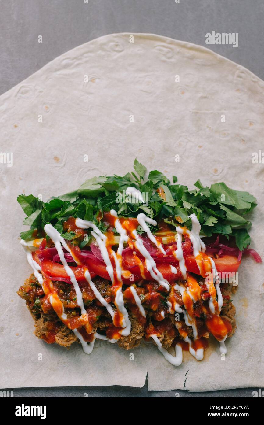 Shawarma preparation. Meat, vegetables and sauce on pita bread. Stock Photo