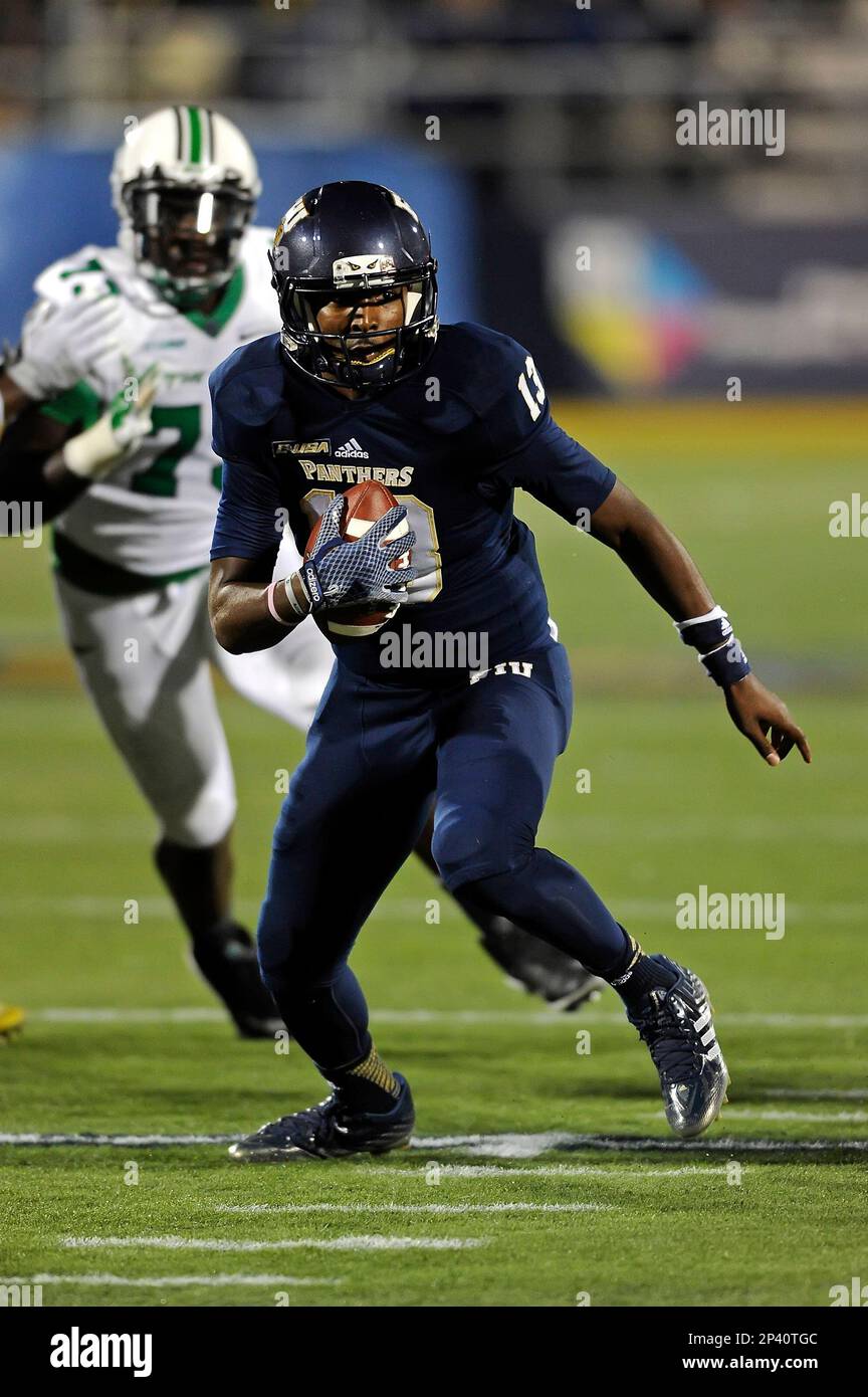 18 October 2014: FIU quarterback Alex McGough (12) carries the ball in the  first half as the Marshall University Thundering Herd defeated the FIU Golden  Panthers, 45-13, at FIU Stadium in Miami,
