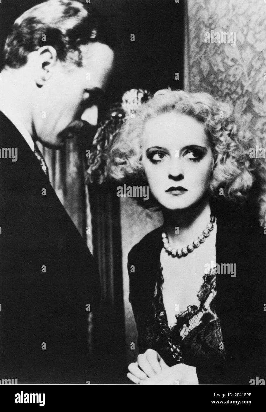 1934 , USA : The movie actress BETTE DAVIS ( 1908 -  1989 ) with LESLIE HOWARD  in OF HUMAN BONDAGE ( Schiavo d' amore ) by John Cromwell , from a novel by W. Somerset Maugham - CINEMA - FILM - attrice - portrait - ritratto  - love scene - scena d' amore - innamorati - lovers - amanti - collana - necklace - lace - pizzo - bijoux - jewels - gioielli - gioielli - jewellery - pearls - perla - perle - bionda - blonde  - profile - profilo ----  Archivio GBB Stock Photo