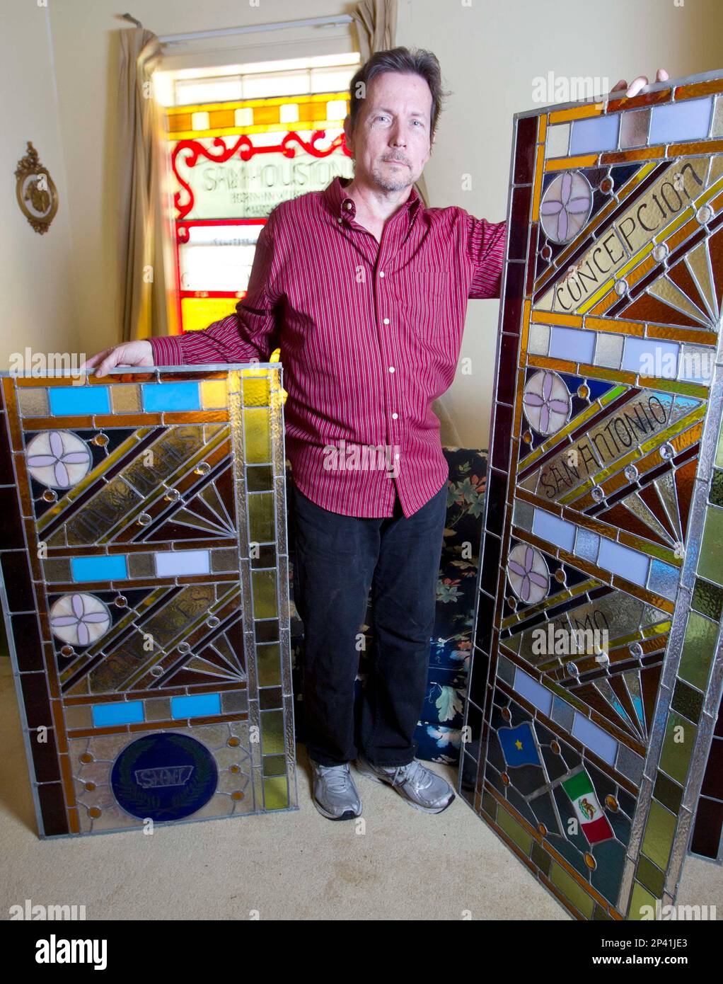 In an Oct. 31, 2014 photo, Sam Houston State University alumnus Joe Janczak  poses with sections of his rebuilt 17-foot stained glass window honoring  Sam Houston and Texas heroes at his home,