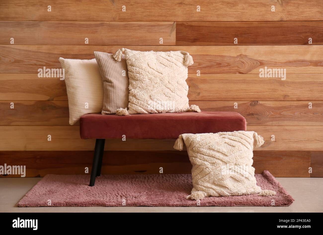 Stylish decorative pillows on bench near wooden wall Stock Photo Alamy