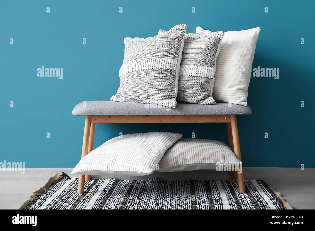 Stylish decorative pillows on bench near blue wall Stock Photo Alamy