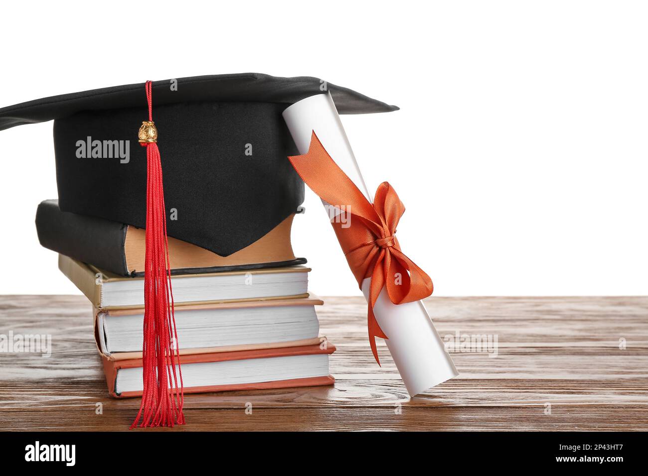 Graduation hat with diploma and books on wooden table against white ...