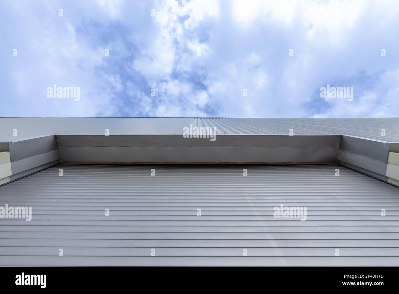 Facade of an industrial building with a retractable metal door seen from a low angle Stock Photo