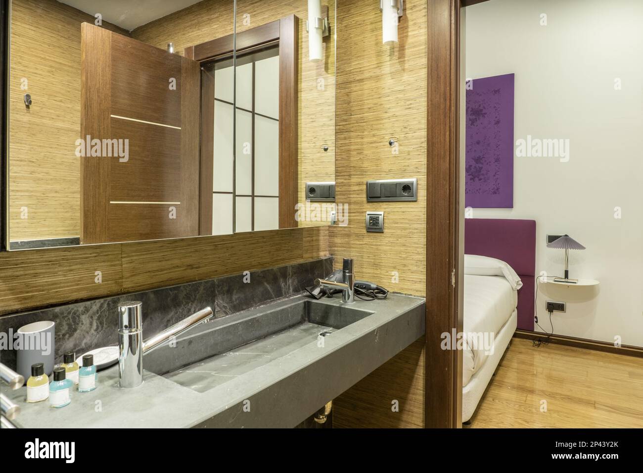 Nice modern bathroom with one-piece black marble sink with two-door mirror  cabinet and exit to a double bedroom Stock Photo - Alamy, image size:1300x955