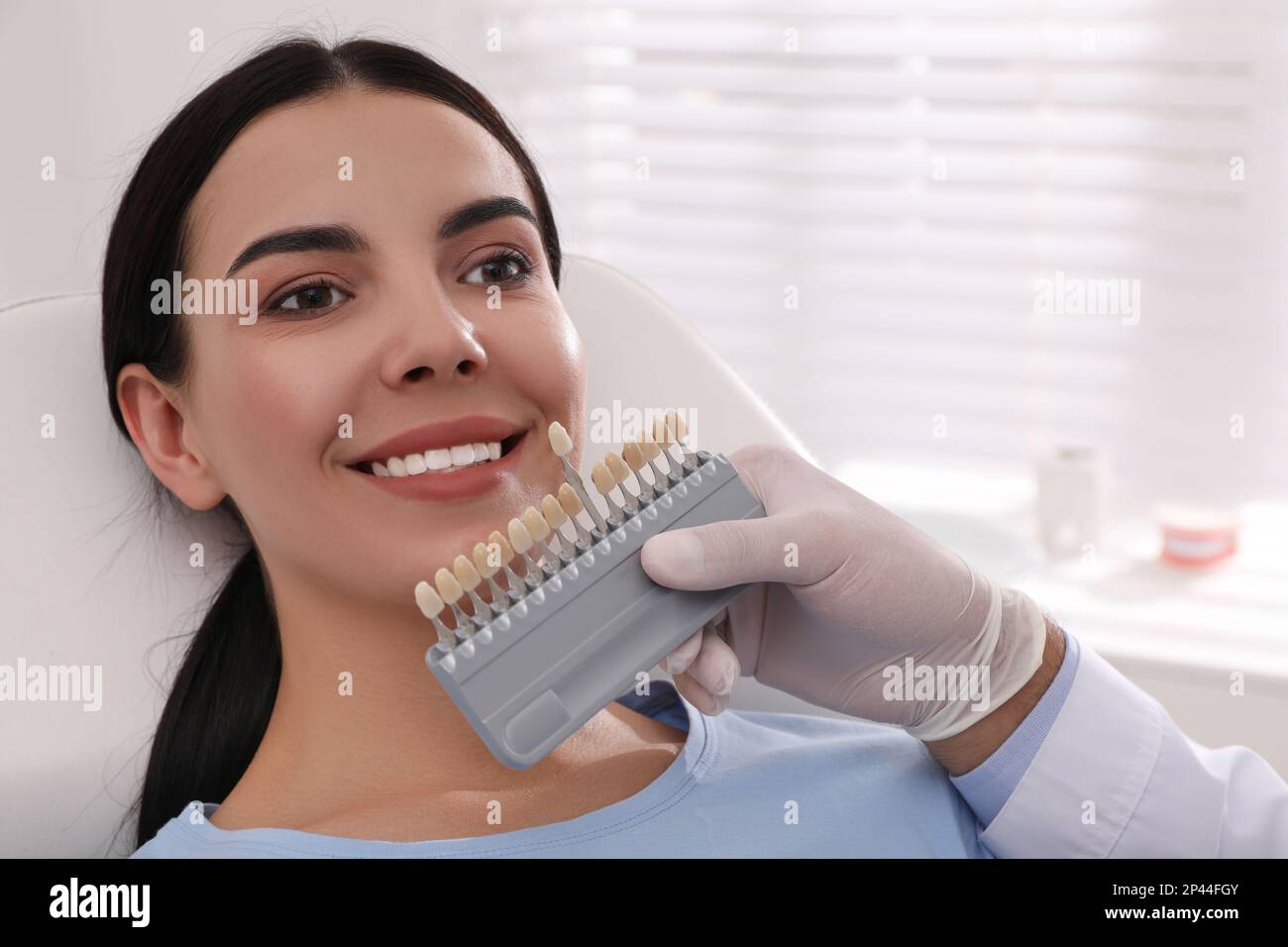 Dentist checking young woman's teeth color in clinic Stock Photo Alamy
