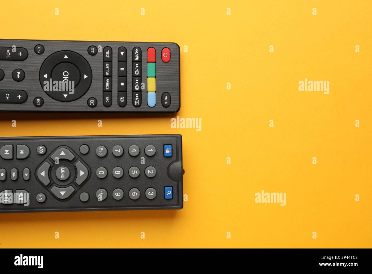 Remote controls on yellow background, flat lay. Space for text Stock Photo