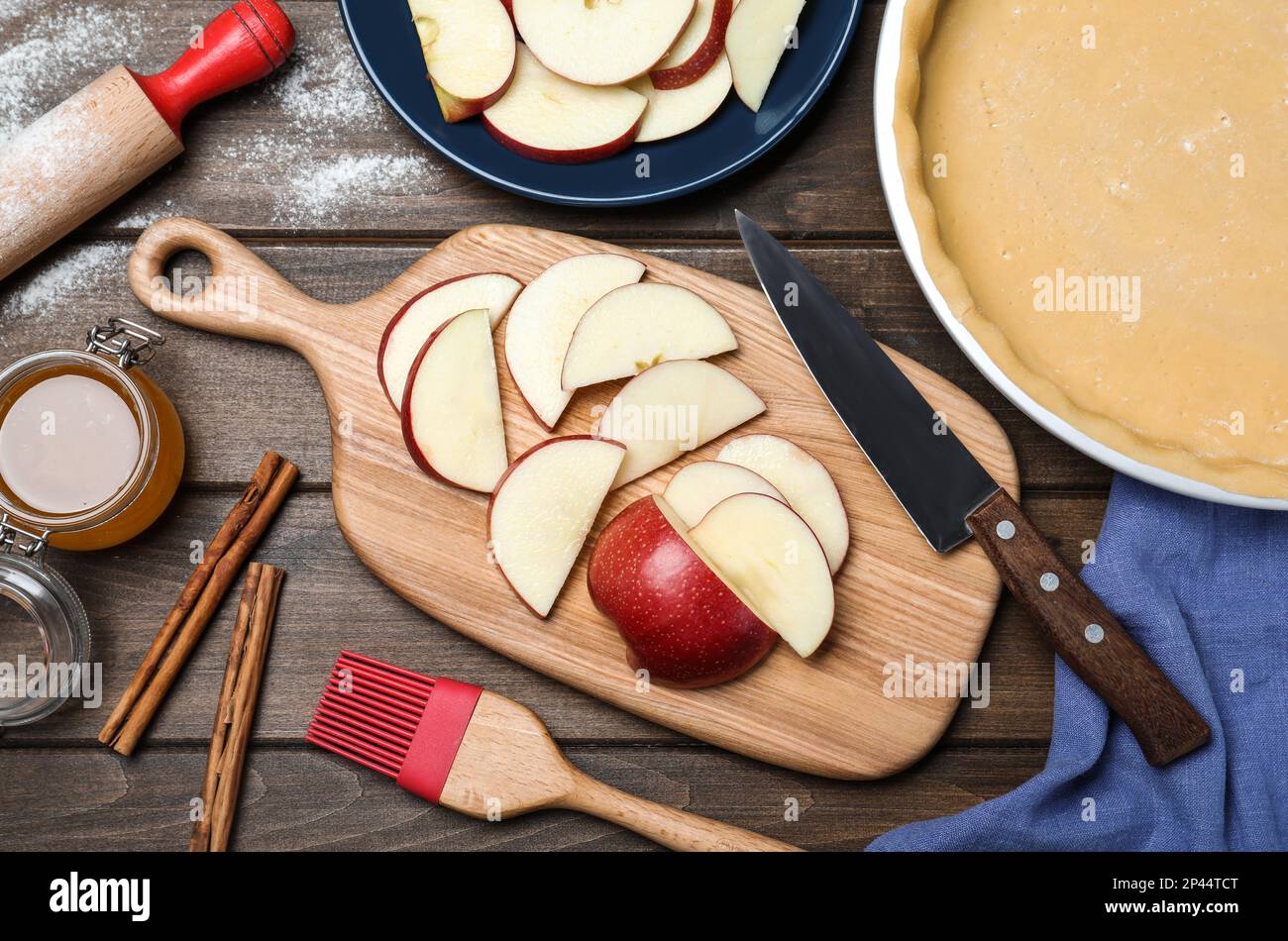 Cut fresh apple with knife and board on wooden table, flat lay. Baking pie Stock Photo