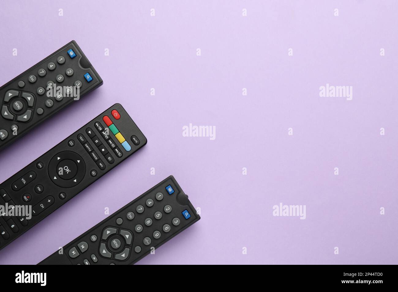 Remote controls on violet background, flat lay. Space for text Stock Photo