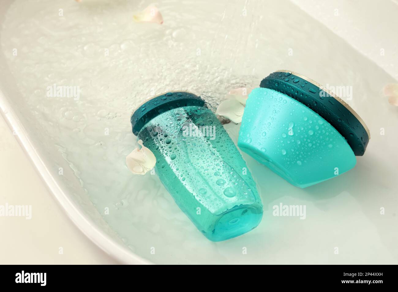 Hair care cosmetic products with flower petals and water in sink Stock