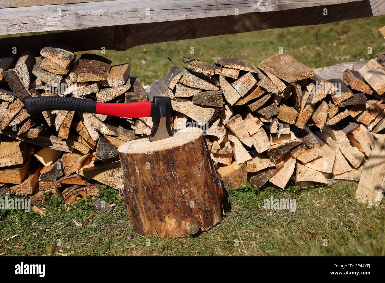 Tree stump with axe and cut firewood outdoors Stock Photo Alamy