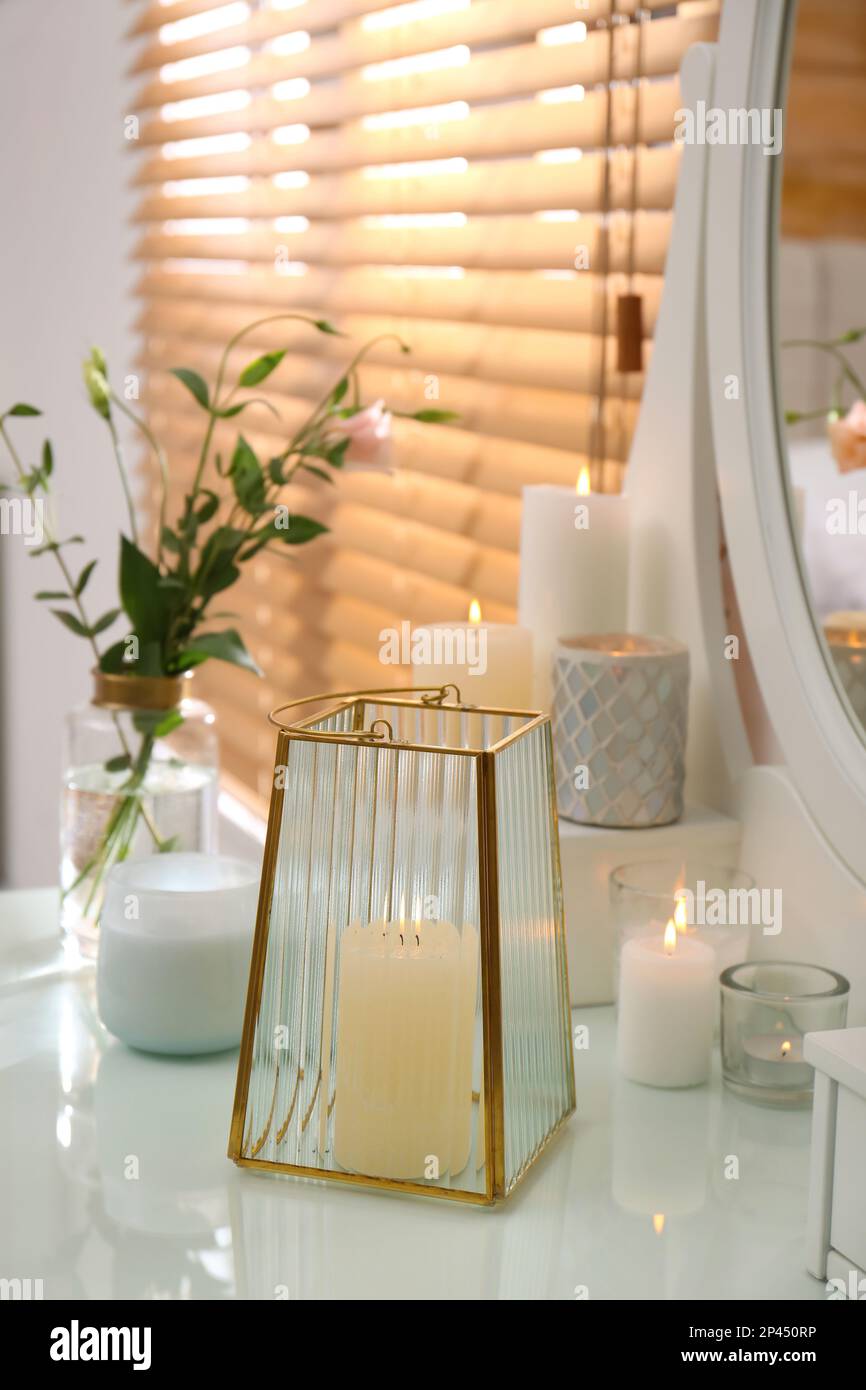 Burning scented candles and bouquet on dressing table indoors Stock