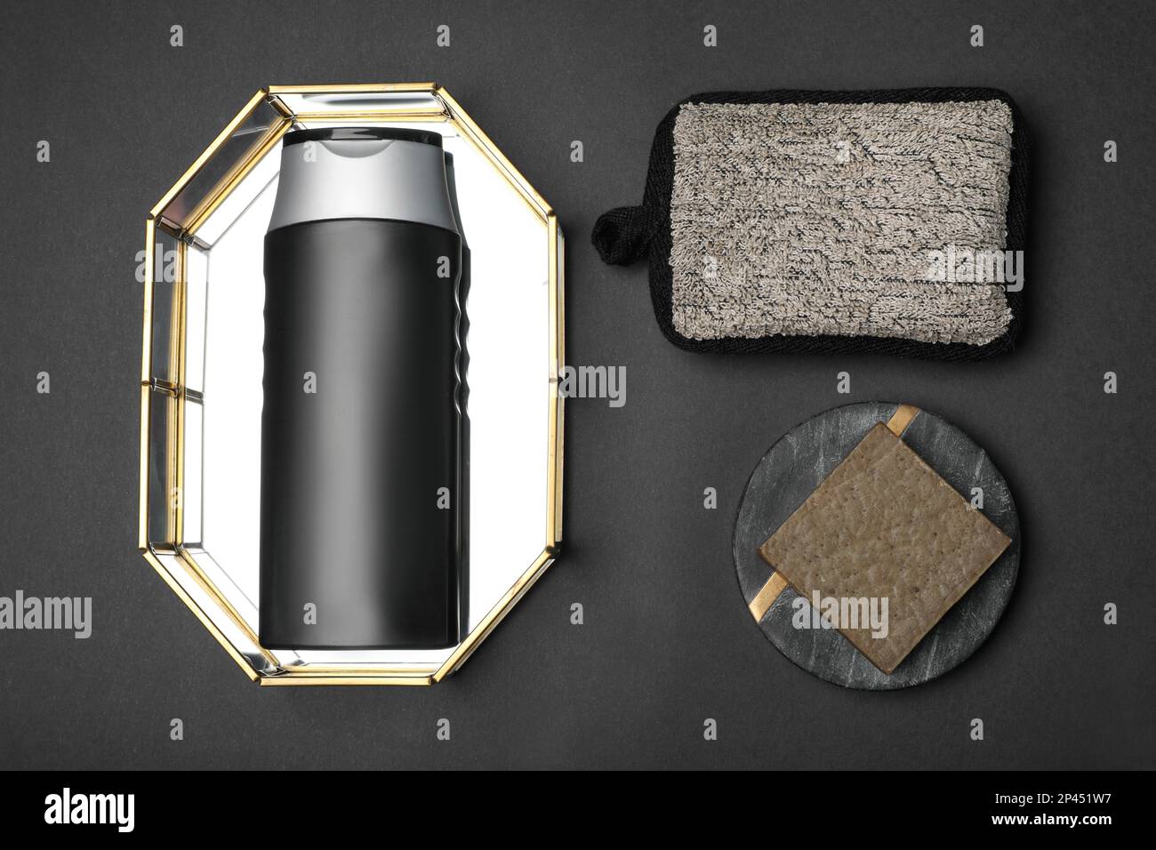 Bottle of shower gel, soap bar and sponge on black background, flat lay