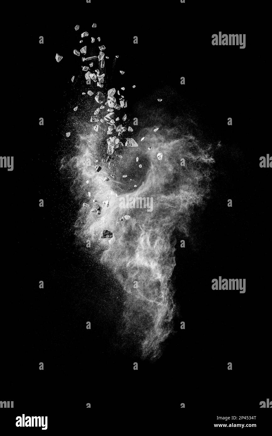Split debris of stone exploding with white dust against black ...