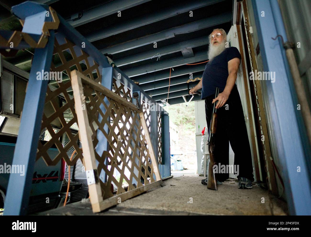 Earl Cook stands with his shotgun on the deck of his Switzer Village