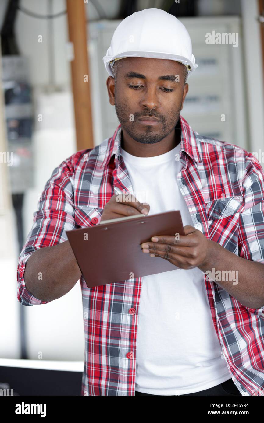serious tradesman writing on clipboard Stock Photo