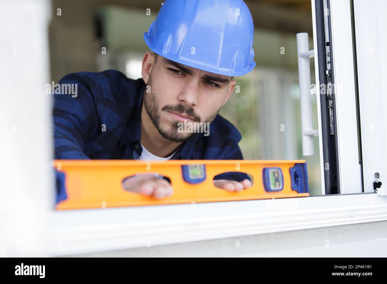 construction worker using bubble level while installing window indoors ...