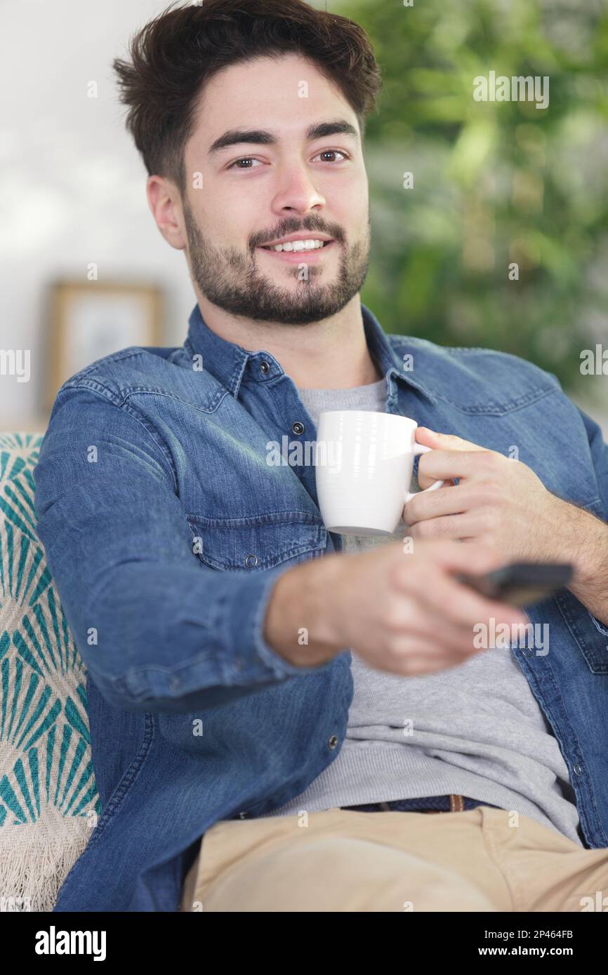 man watching tv while drinking coffee Stock Photo