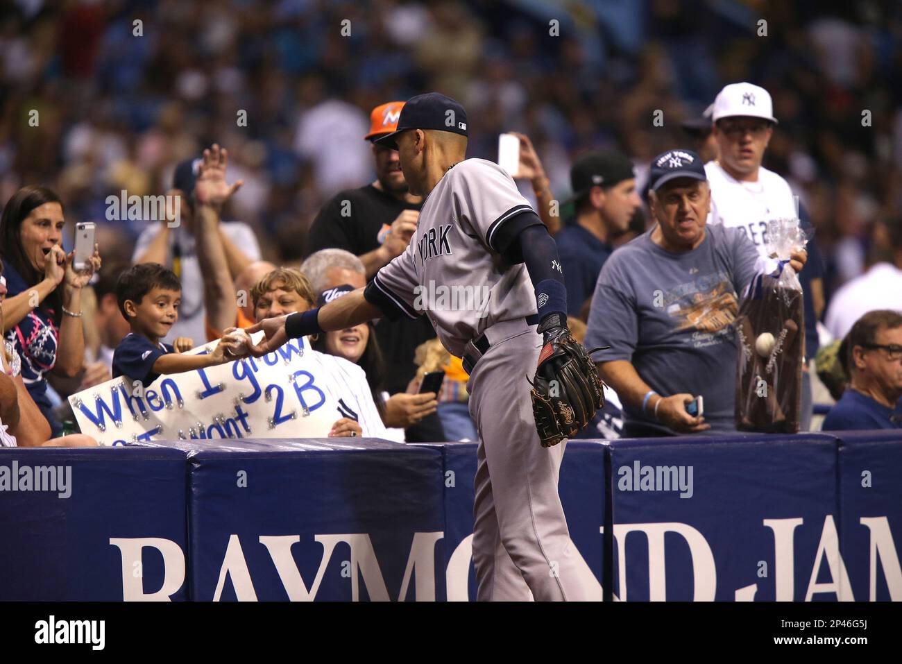 New York Yankees shortstop Derek Jeter (2) hands a ball to a young fan  between innings during a major league baseball game between the New York  Yankees and the Tampa Bay Rays