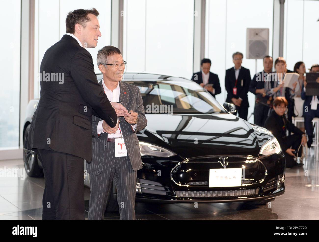 Elon Musk (L), CEO of Tesla Motors Inc. gives a key of Tesla Elon Musk (L), CEO of Tesla Motors Inc. gives a key of Tesla