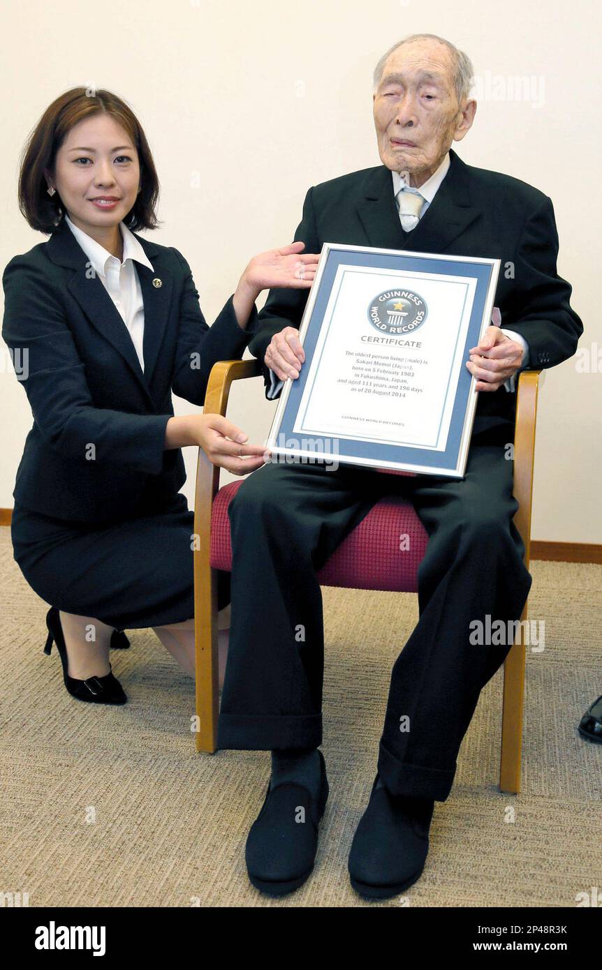Sakari Momoi, a 111-year-old Japanese retired educator, poses for a photo  after receiving a certificate from a Guinness World Records official, left,  in Tokyo Wednesday, Aug. 20, 2014. Momoi was recognized as