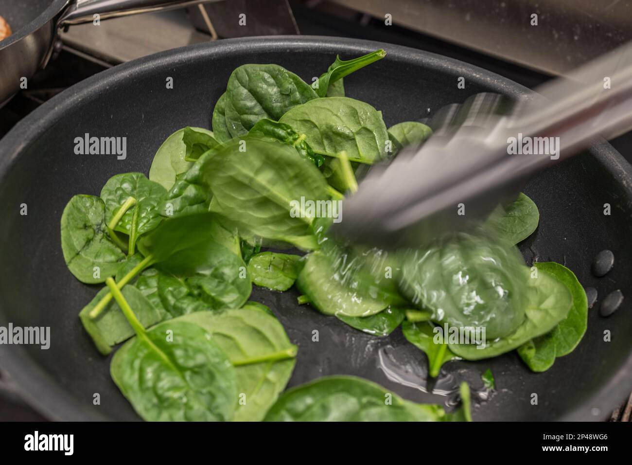 Action in the kitchen, some spinach being lightly heated in the fry pan