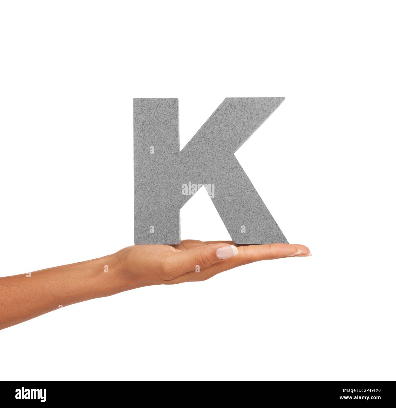 Showing you the letter K. A young woman holding a capital letter K isolated on a white background. Stock Photo