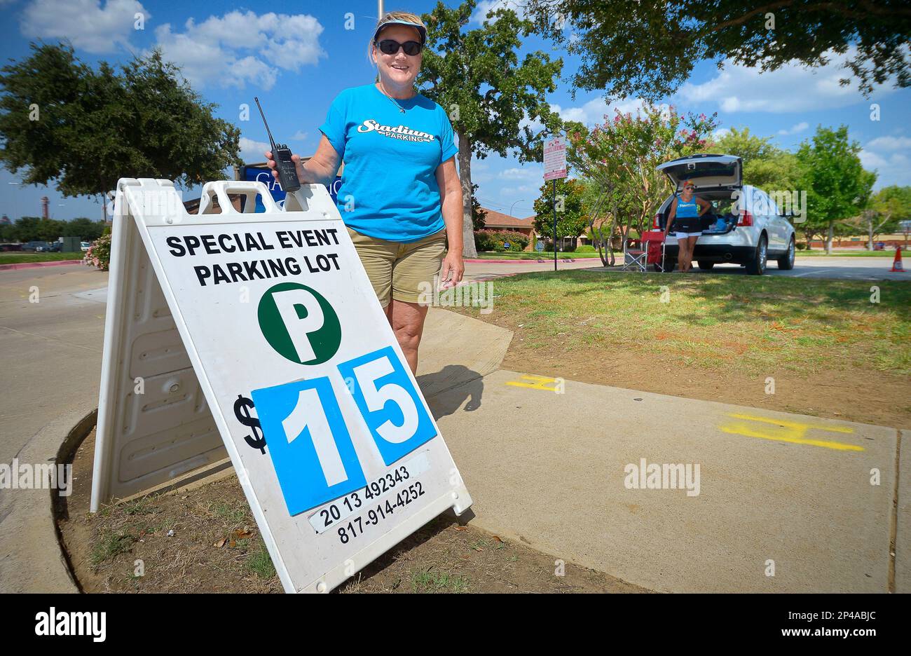 In this Saturday, July 26, 2014, photo, Sharon Smith tries to attract  motorists to a parking space at a Stadium Parking across the street from  Globe Life Park in Arlington, Texas. After