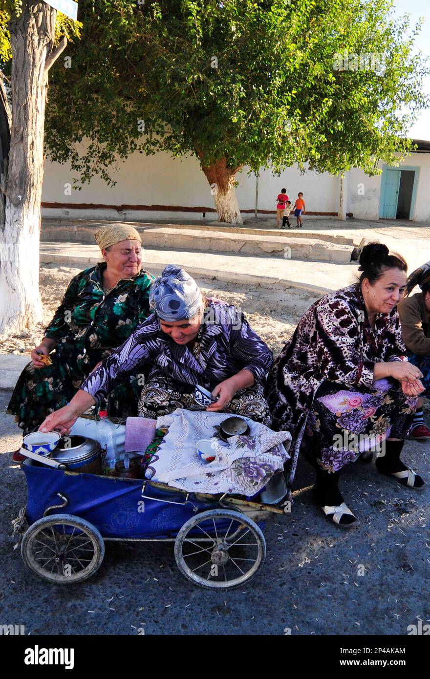 Uzbek women selling tea from an old vintage baby carriage in Bukhara, Uzbekistan. Stock Photo