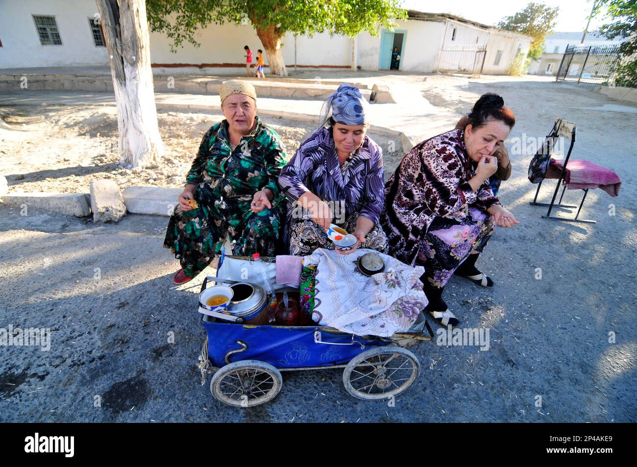 Uzbek women selling tea from an old vintage baby carriage in Bukhara, Uzbekistan. Stock Photo